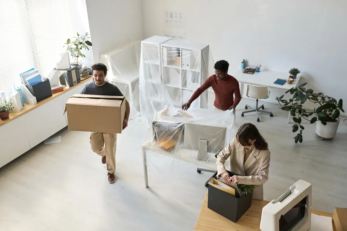 Transfert de bureaux : déménageurs déplaçant des cartons et du mobilier de siège