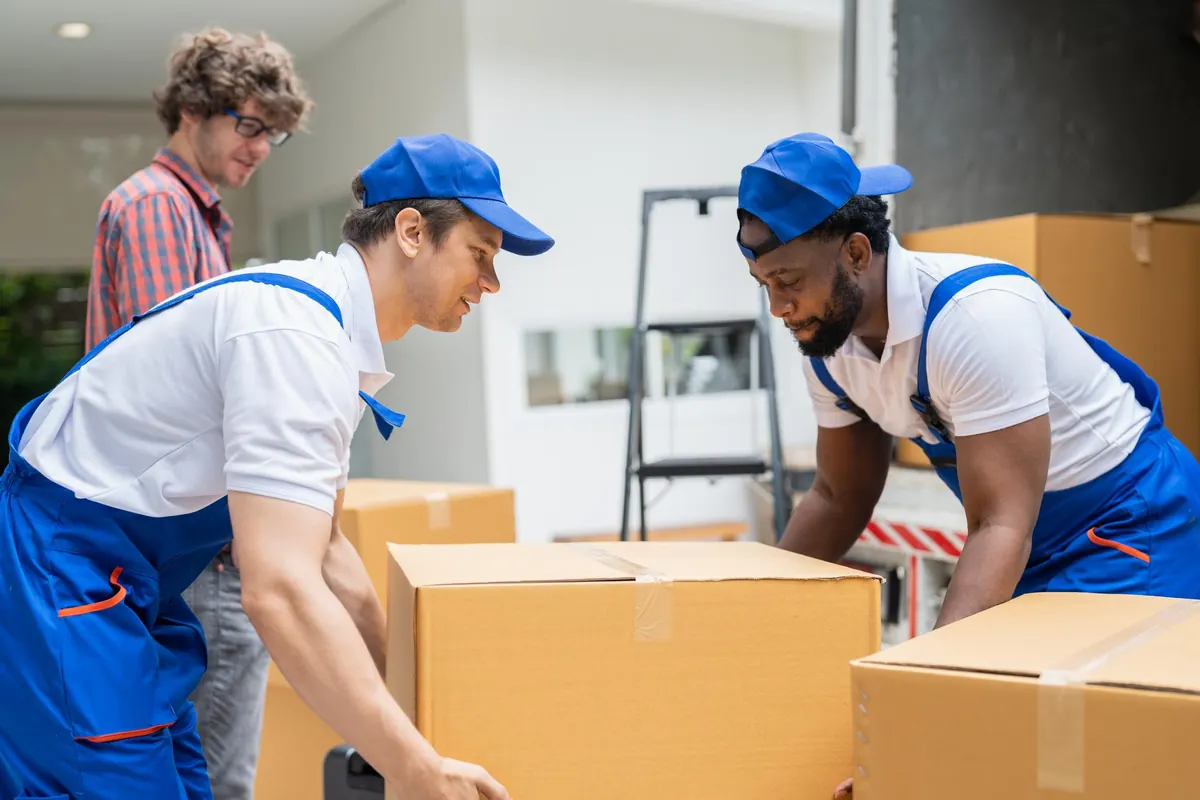 Déménageurs en uniforme préparant un carton renforcé pour un déménagement à Dakar